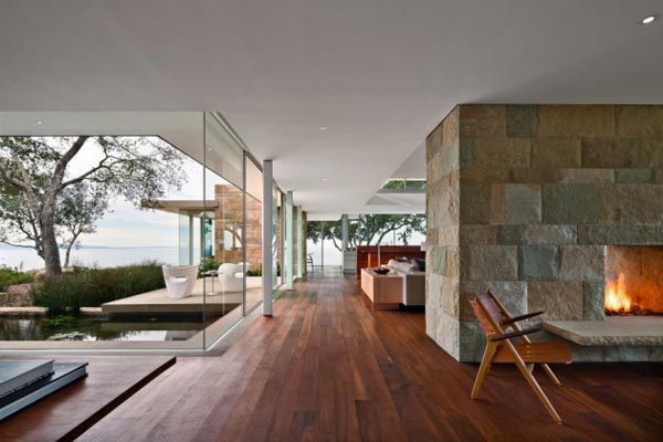 Dark floorboards in combination with open spaces, glass, and rough stone walls.