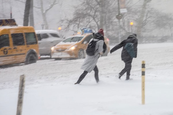 Some people struggling their way through the snow and the storm.