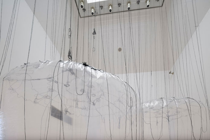 Yasuaki Onishi, attached to the ceiling with numerous threads.