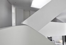 The space is characterized by the curvilinear forms of the staircase and the different floors.