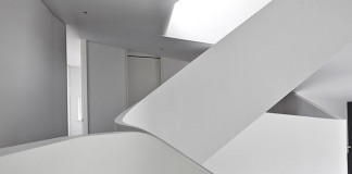 The space is characterized by the curvilinear forms of the staircase and the different floors.